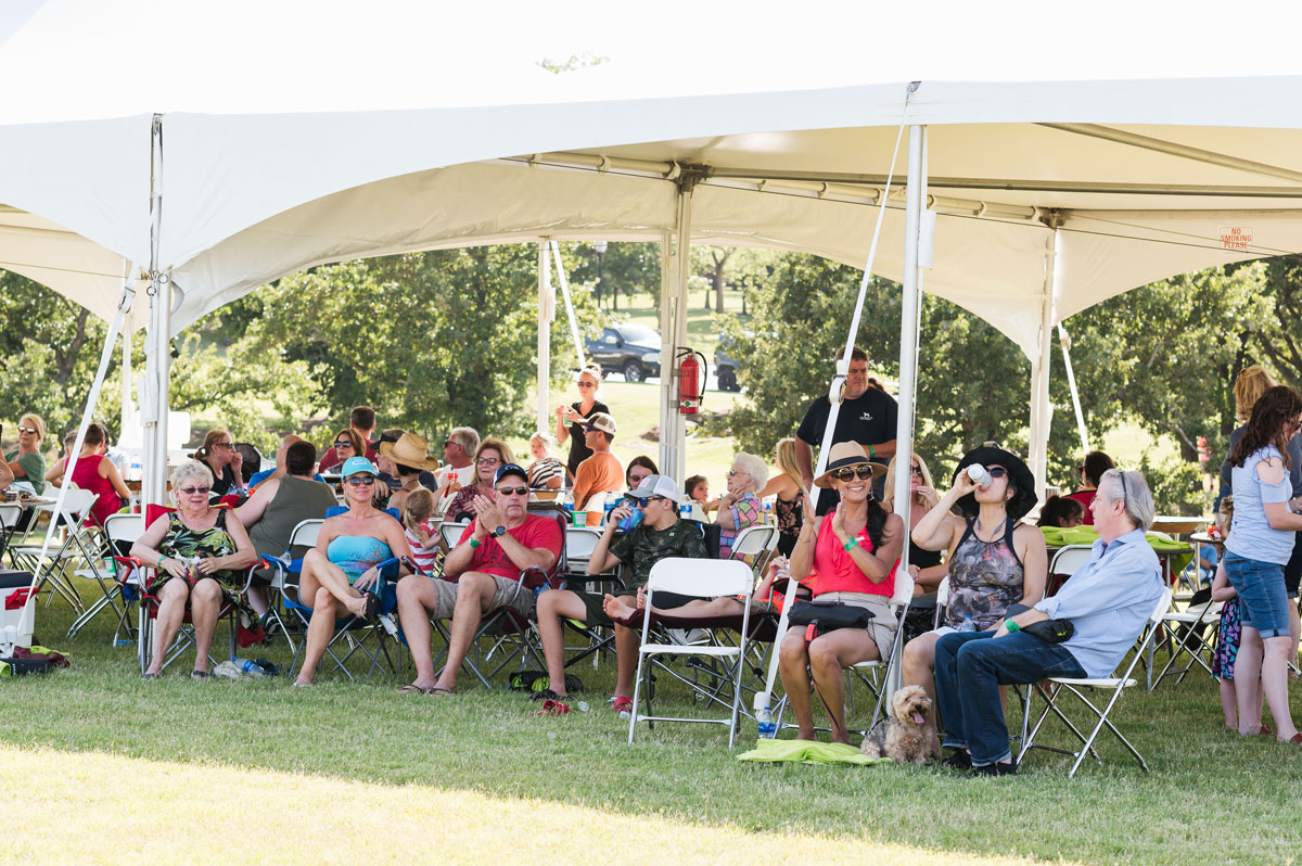 Attendees enjoying live music and shaded seating.